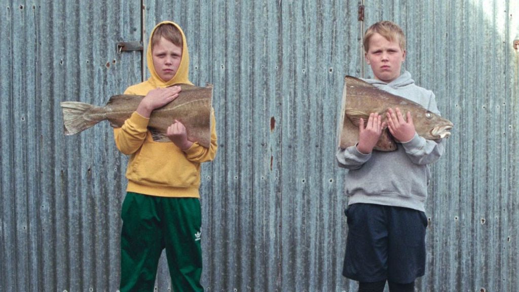 Image of two boys each holding one half of a split fish